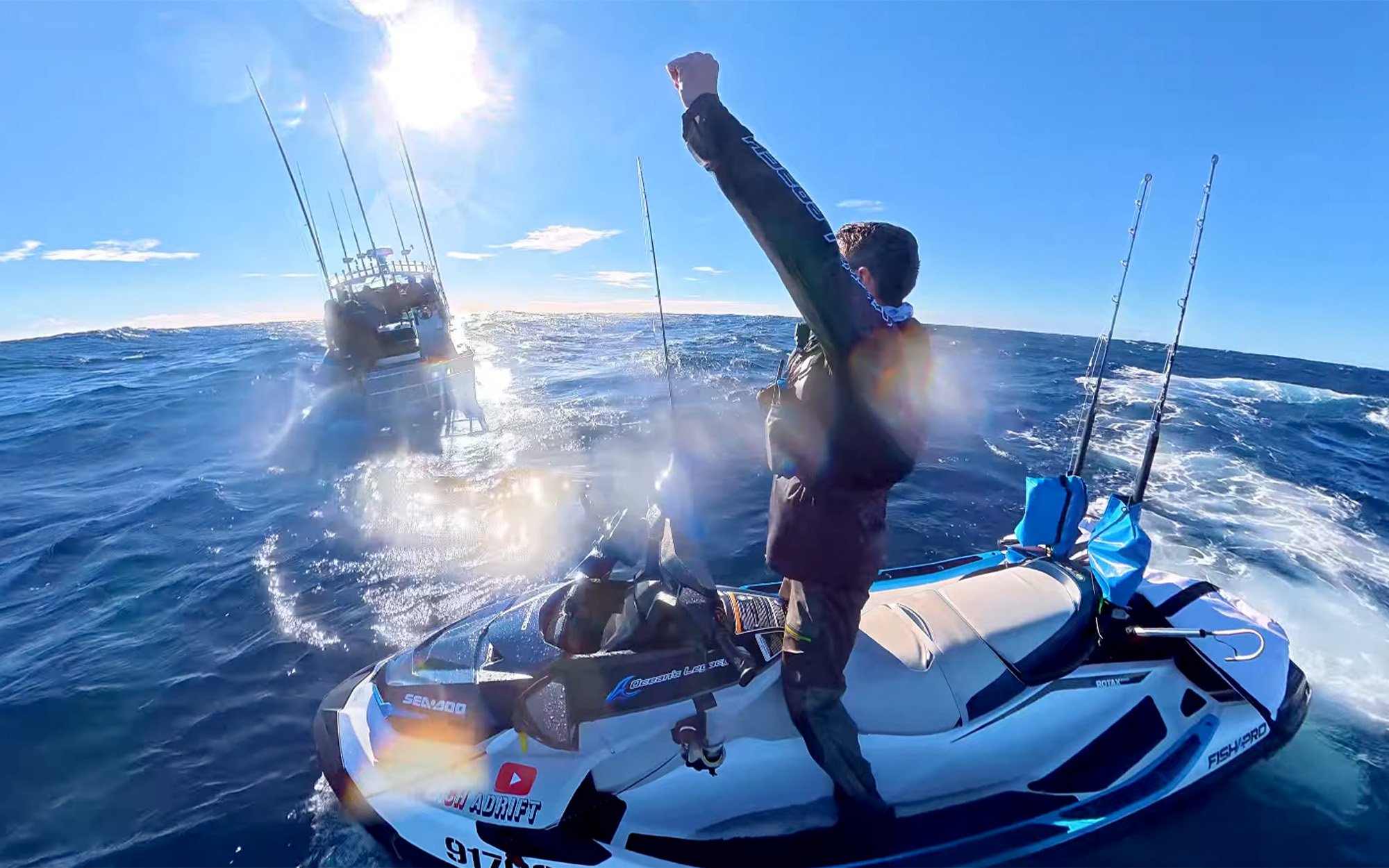A fisherman on a jet ski pumps his fist in the air.