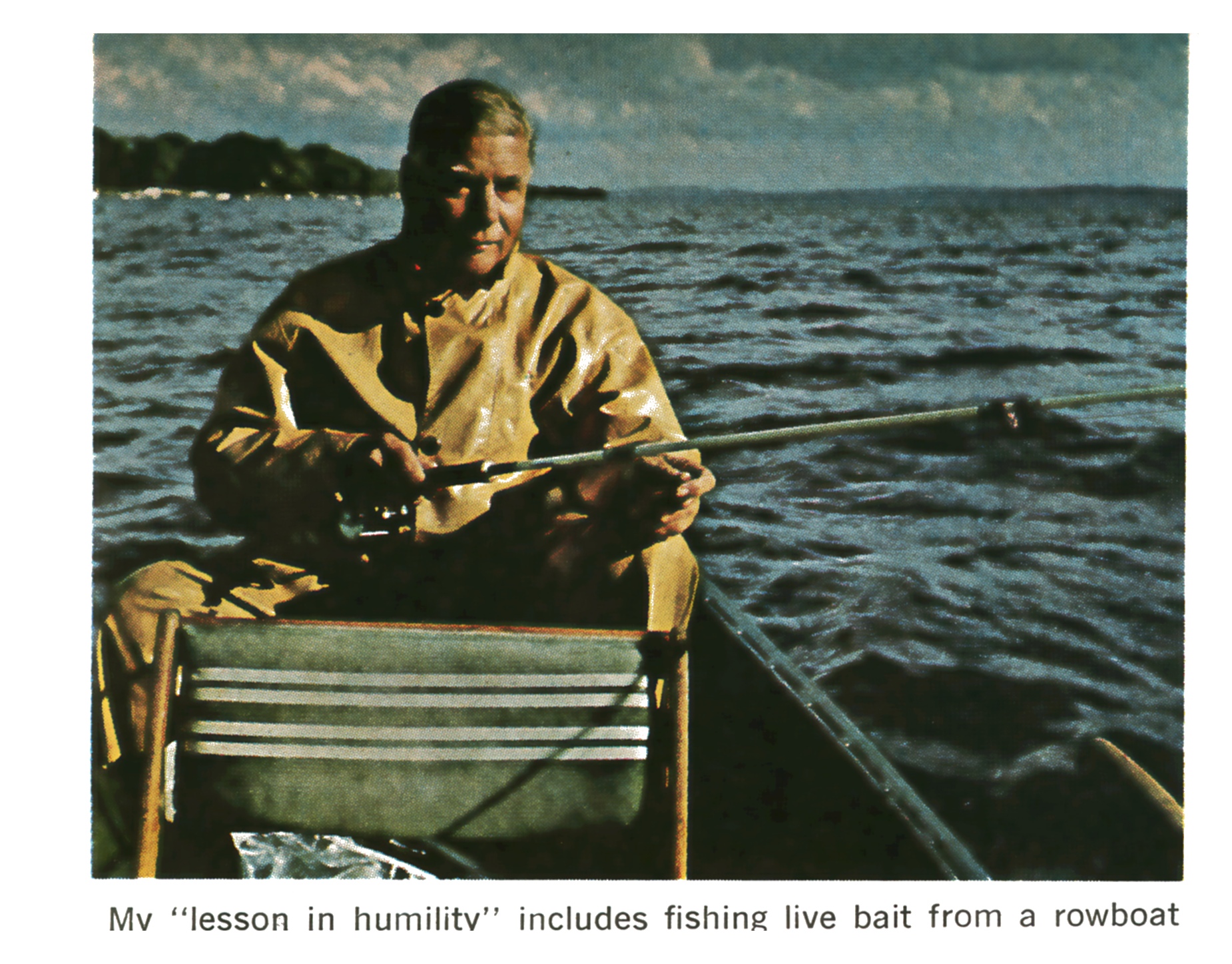 A man in a tan rain jacket fishes with a light rod from a wooden rowboat on open water.