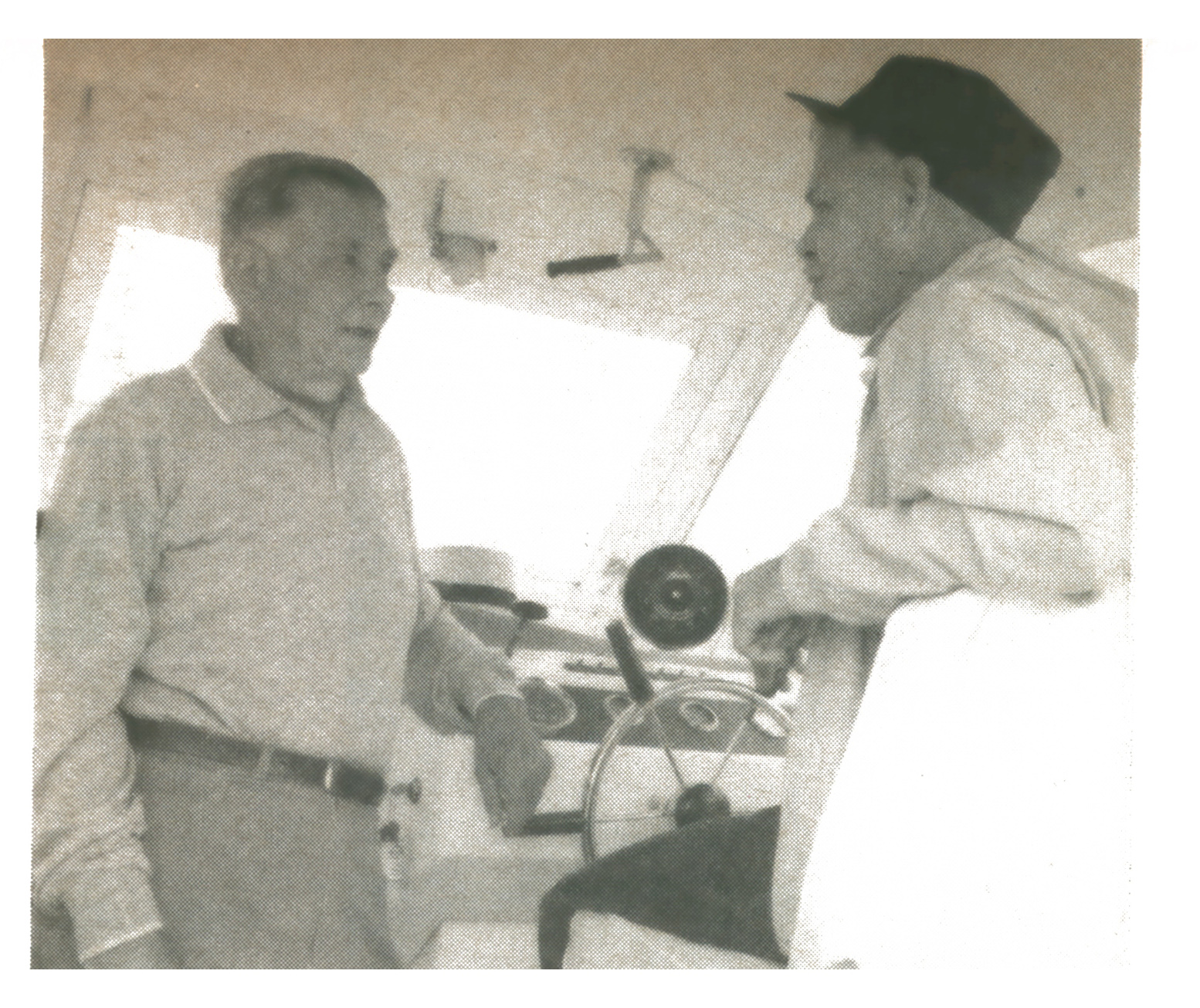 Black-and-white photo of two men, author Cecil Heacox and fisheries manager Bill Shepherd, talking beside the wheel in a boat cabin.
