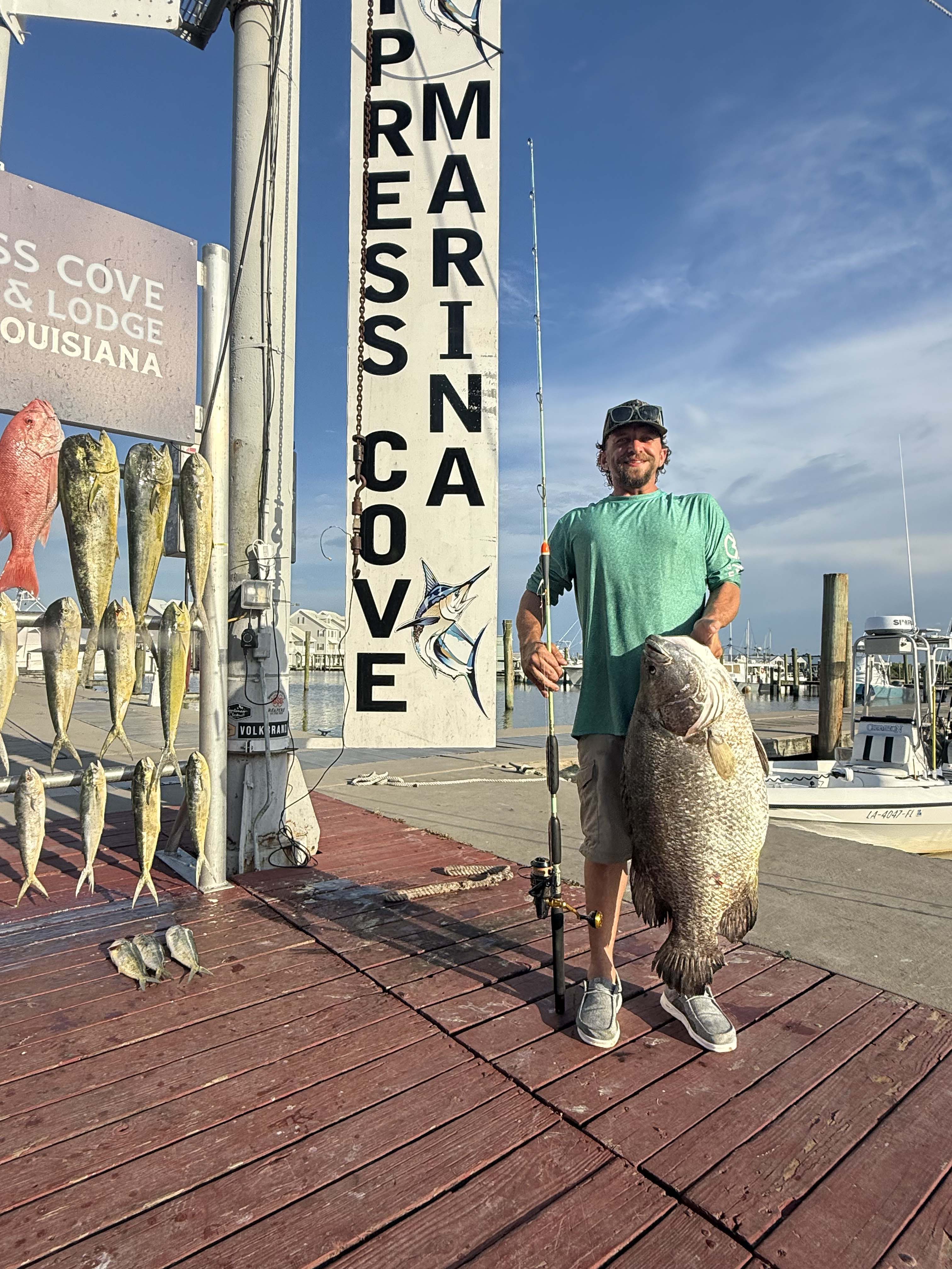 Ryan Stogner with a big tripletail on a dock at the Cypress cove marina