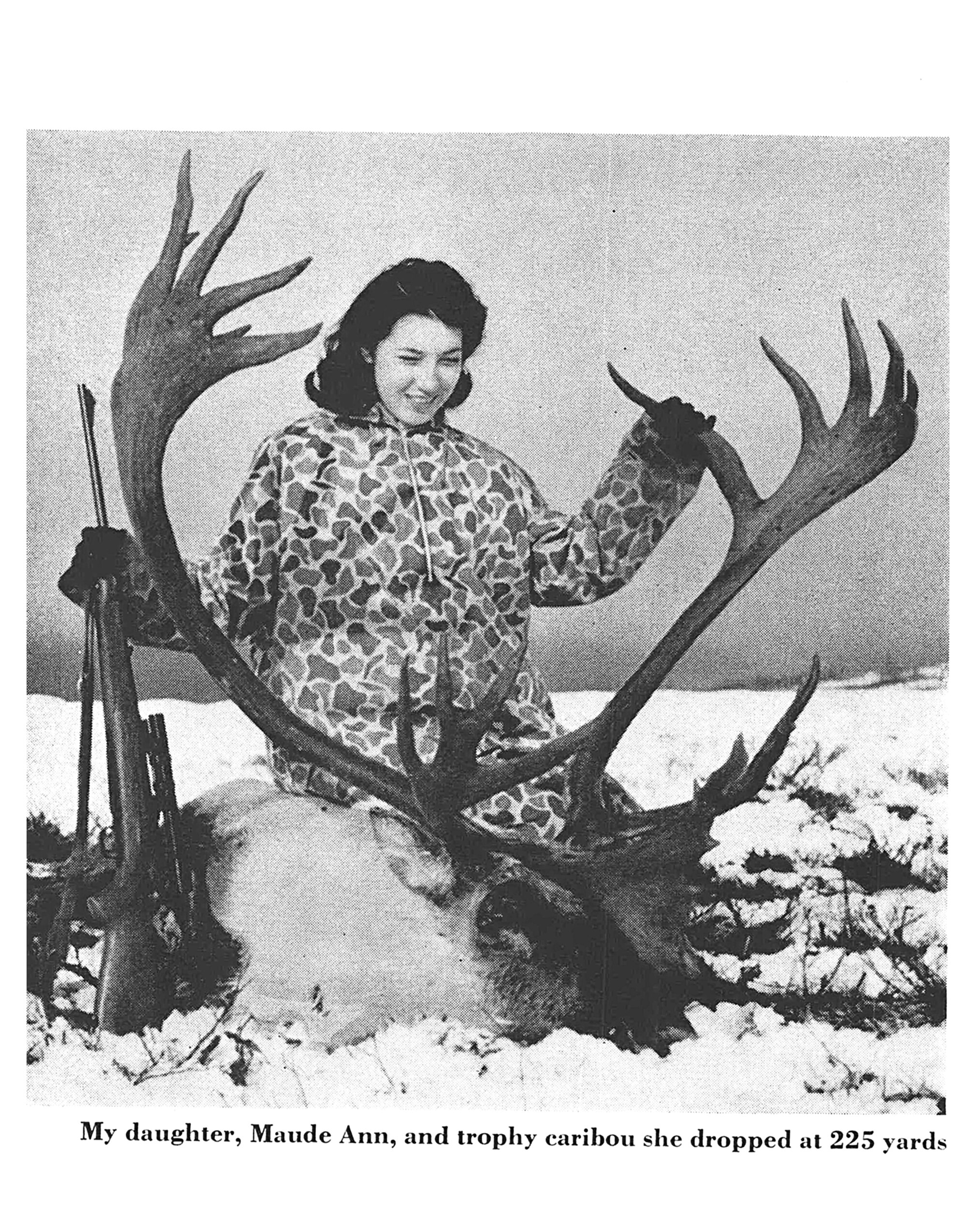 A black and white vintage photo of a woman in a camo suit with a big bull caribou.