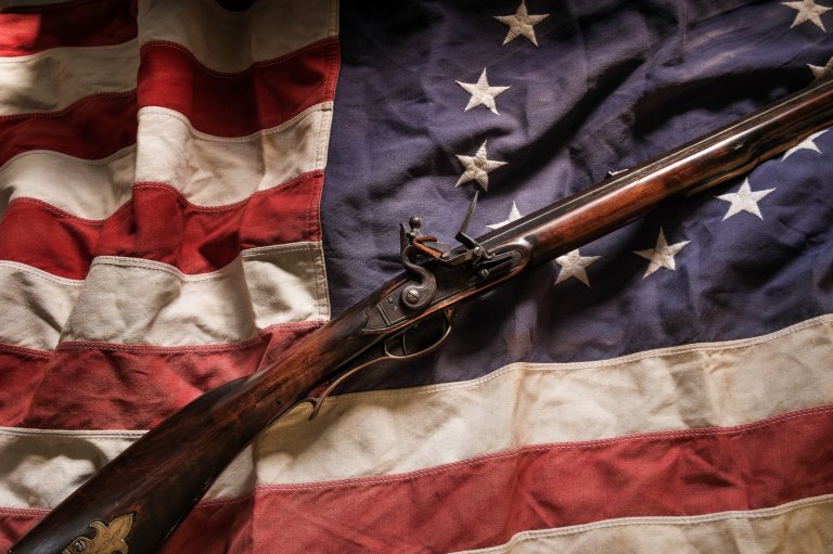 A flintlock rifle on an old american flag