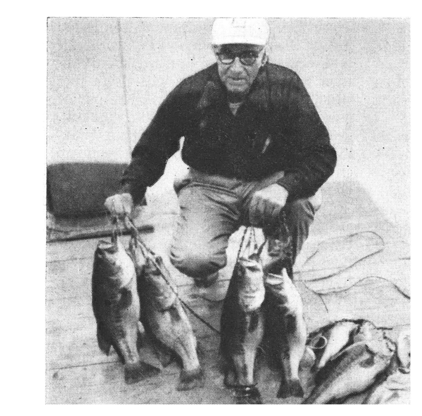 Sam Welch, wearing glasses and a dark jacket, kneels on a dock displaying a heavy stringer of largemouth bass.