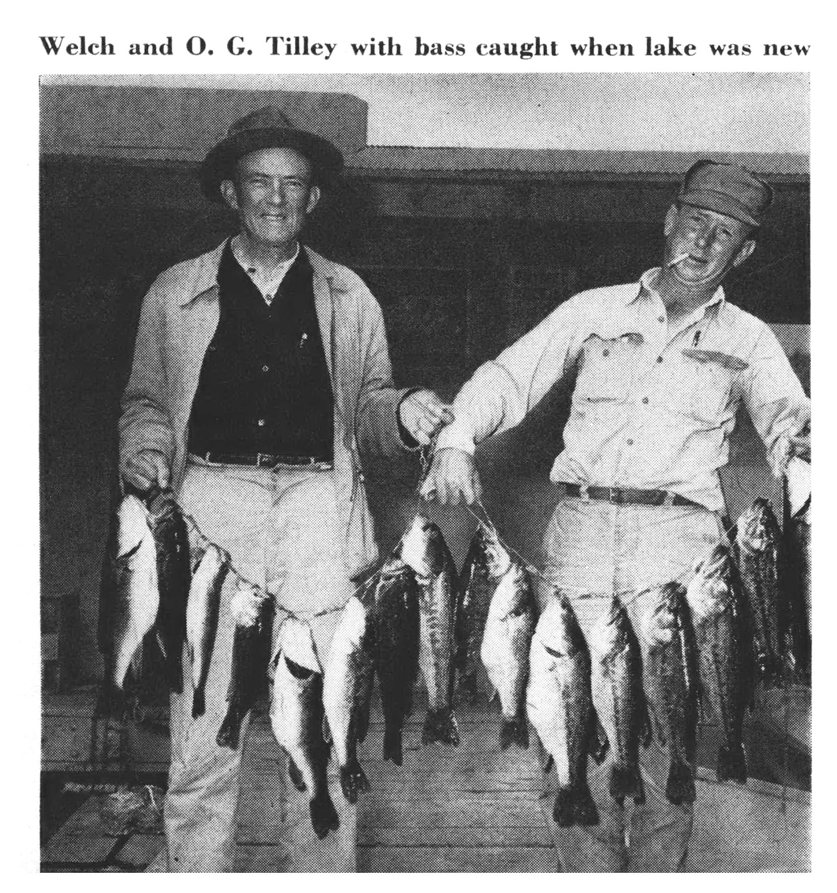 Sam Welch and O. G. Tilley stand indoors holding two long stringers of bass caught when Bull Shoals Lake was new.