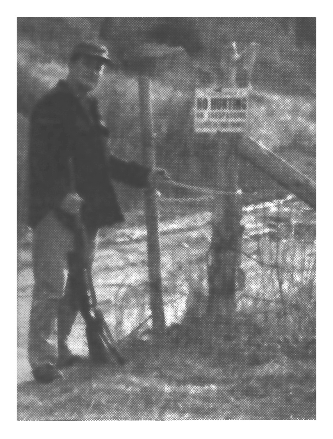 Black-and-white photo of rancher Pete Vandolah standing with a rifle beside a padlocked gate and a 'No Hunting' sign on the Bear Trap Road.