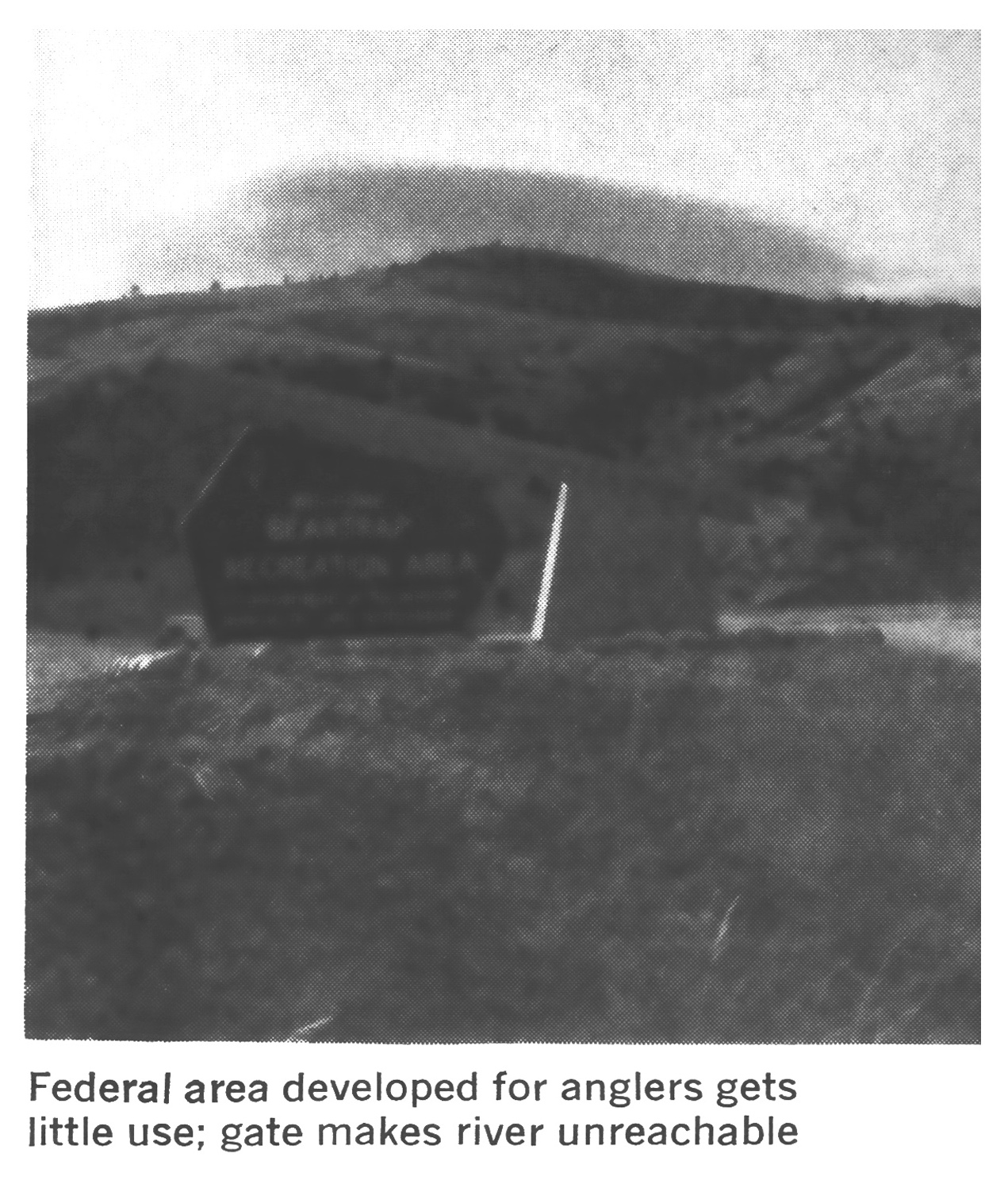 Black-and-white photo of a Bear Trap Recreation Area sign on a grassy hillside at a little-used federal river-access site.