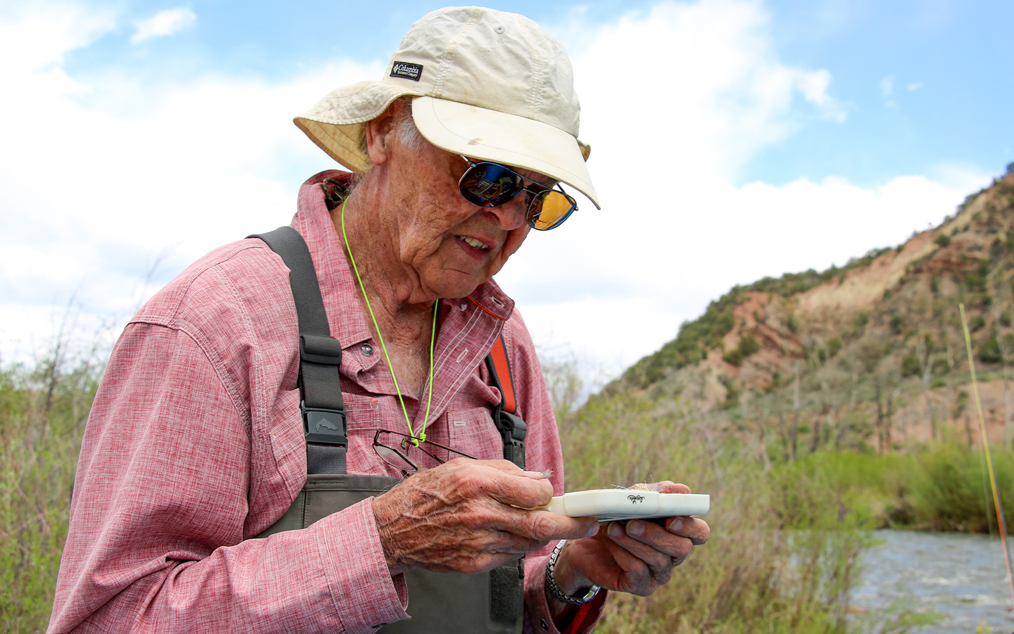 An elderly fly fisherman examines a box of flies.