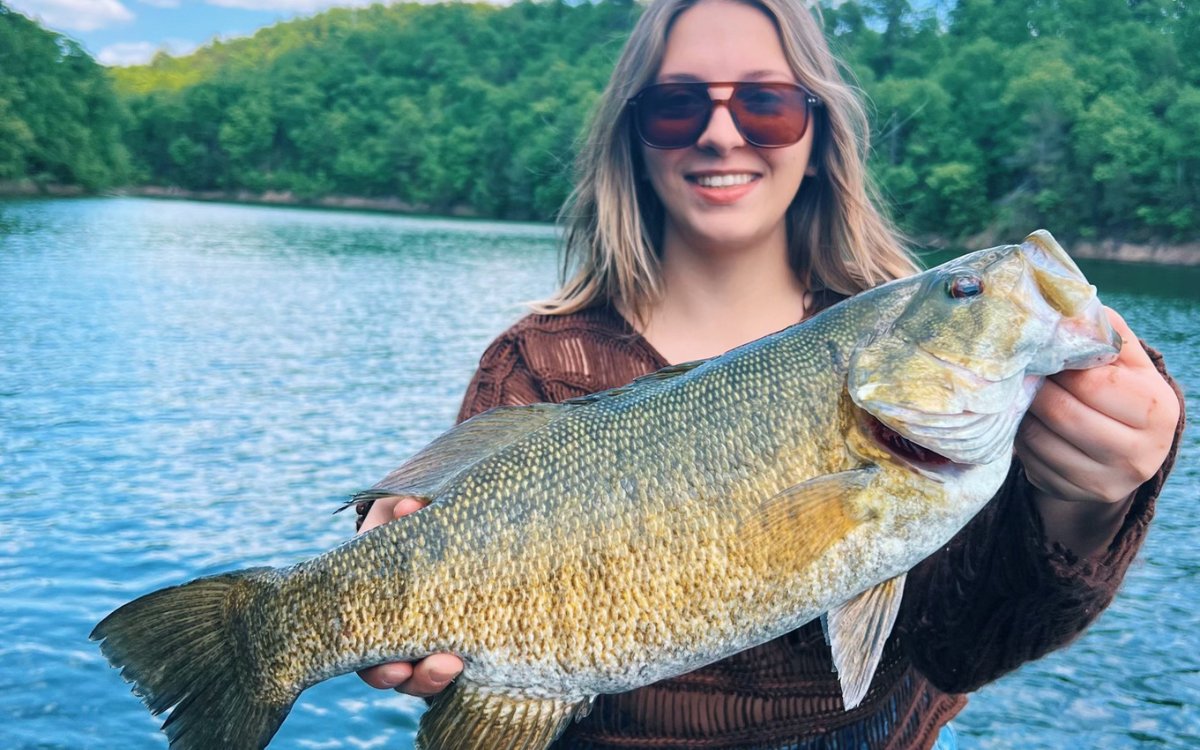 The author's girlfriend holds up a big smallmouth bass she caught