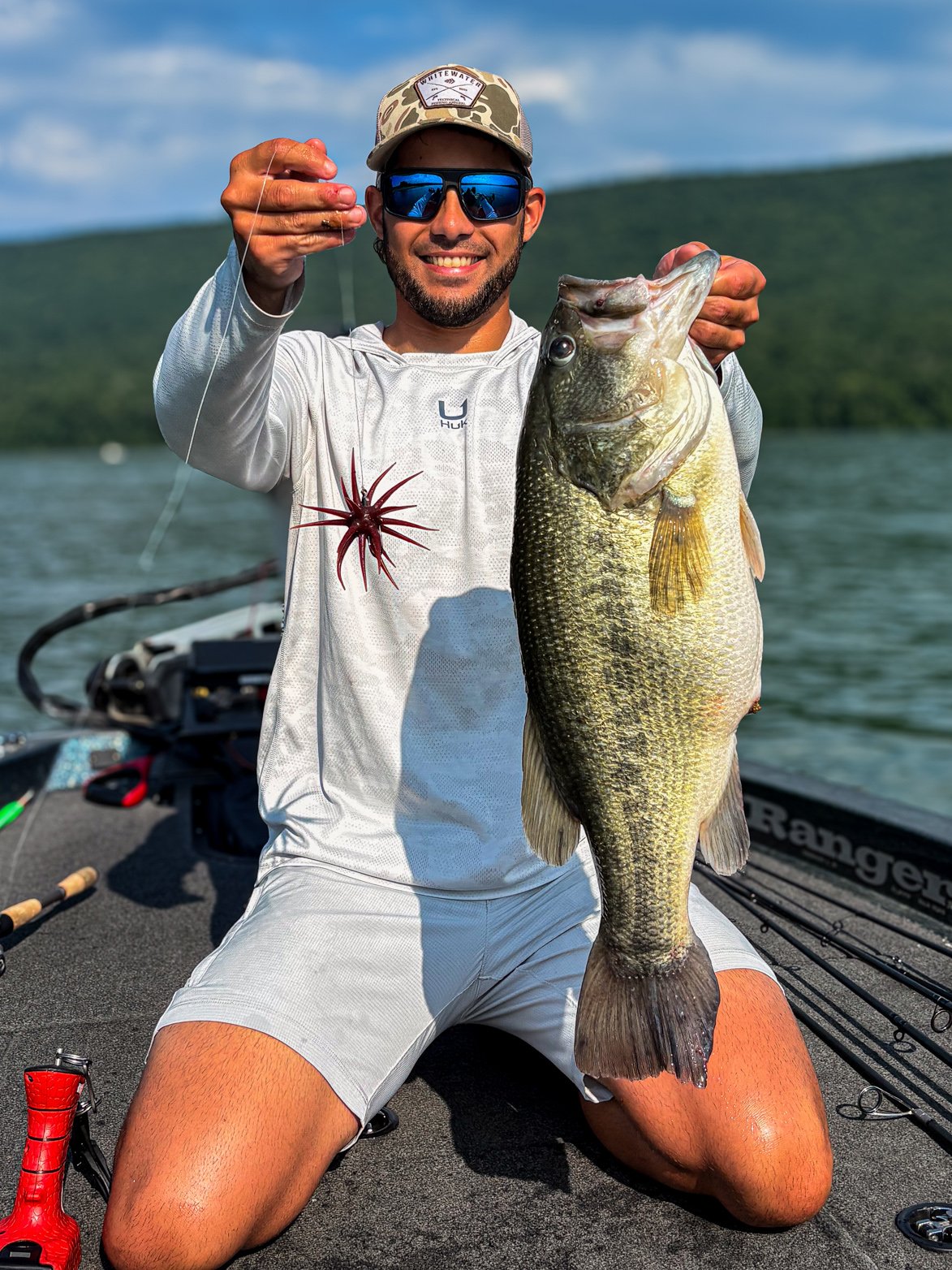 A fisherman holds up a purple urchin bait beside a nice 8 pound bass it caught.