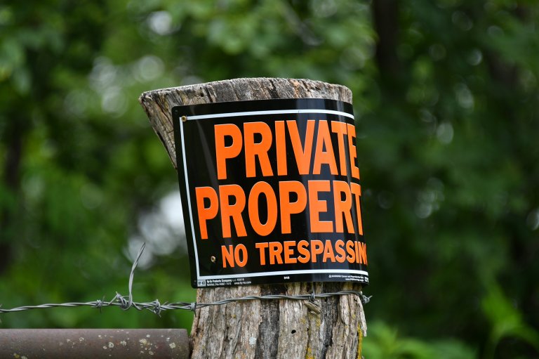A private property no trespassing sign on a fencepost