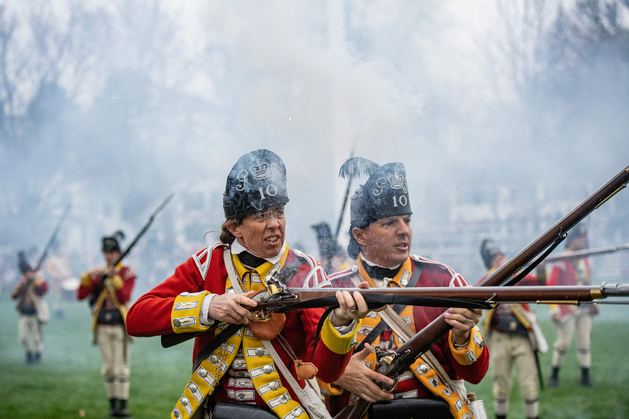 Reenactors dressed as a British soldiers fire during a battle reenactment of the Battle of Lexington and Concord.