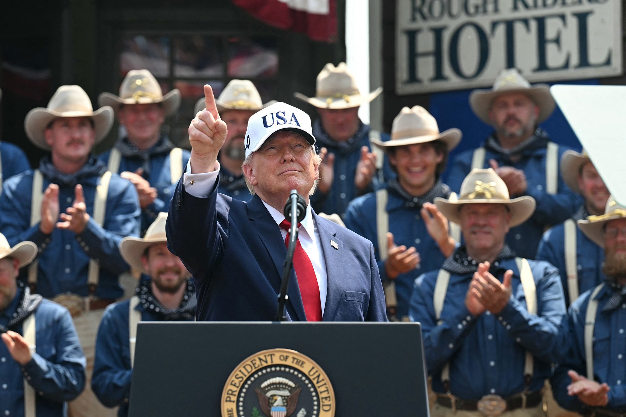 US President Donald Trump gestures as he delivers remarks onstage, flanked by Rough Riders re-enactors, portraying the 1st United States Volunteer Cavalry, at the Burning Hills Amphitheatre after attending the opening of the Theodore Roosevelt Presidential Library in Medora, North Dakota, on July 1, 2026. (Photo by SAUL LOEB / AFP via Getty Images)