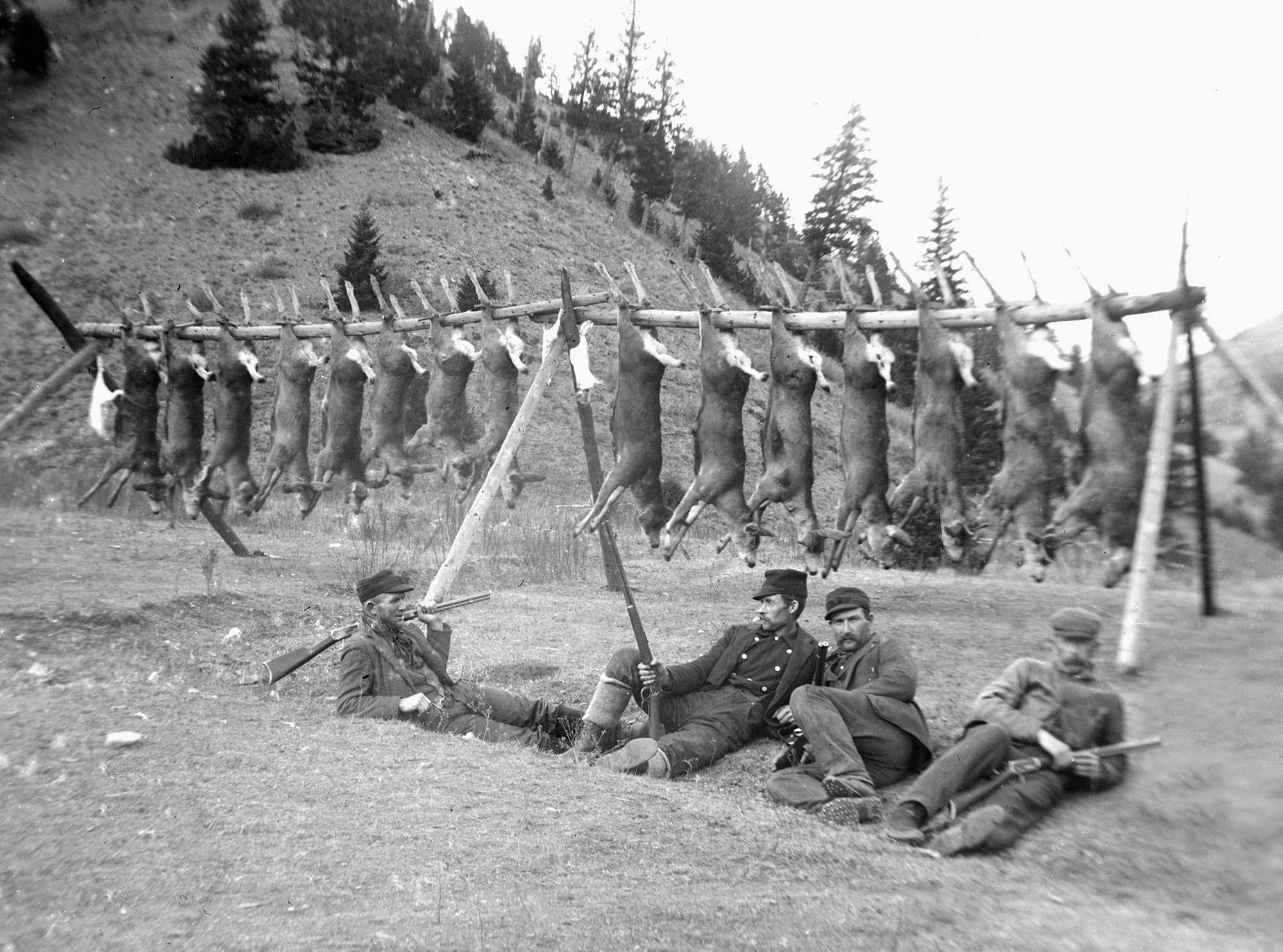 A turn of the century hunting party sprawls out in front of their trophy deer hanging on a pole. (Photo by Kirn Vintage Stock/Corbis via Getty Images)