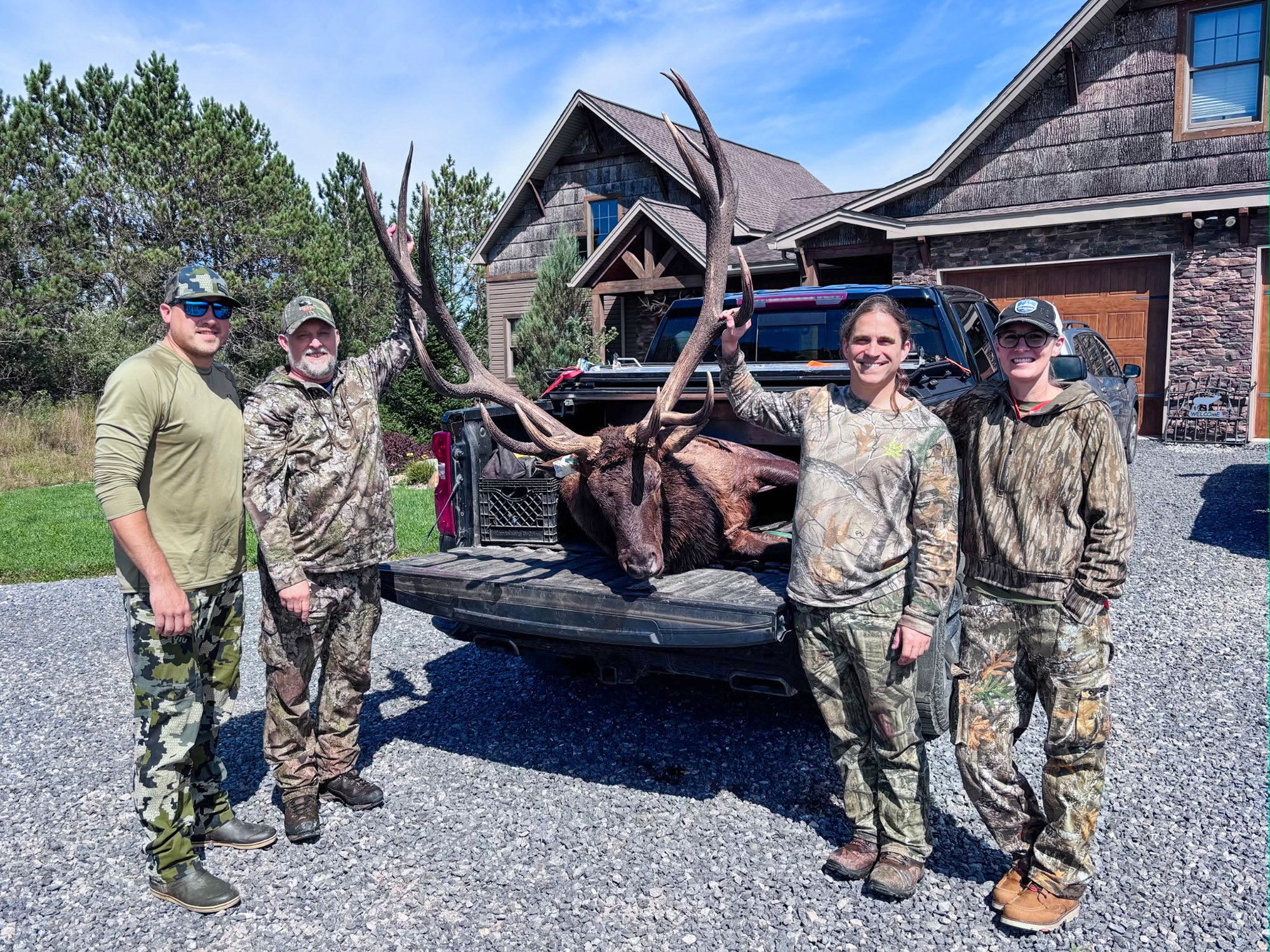 Four hunters around the pending PA state-record bull elk in a truck.