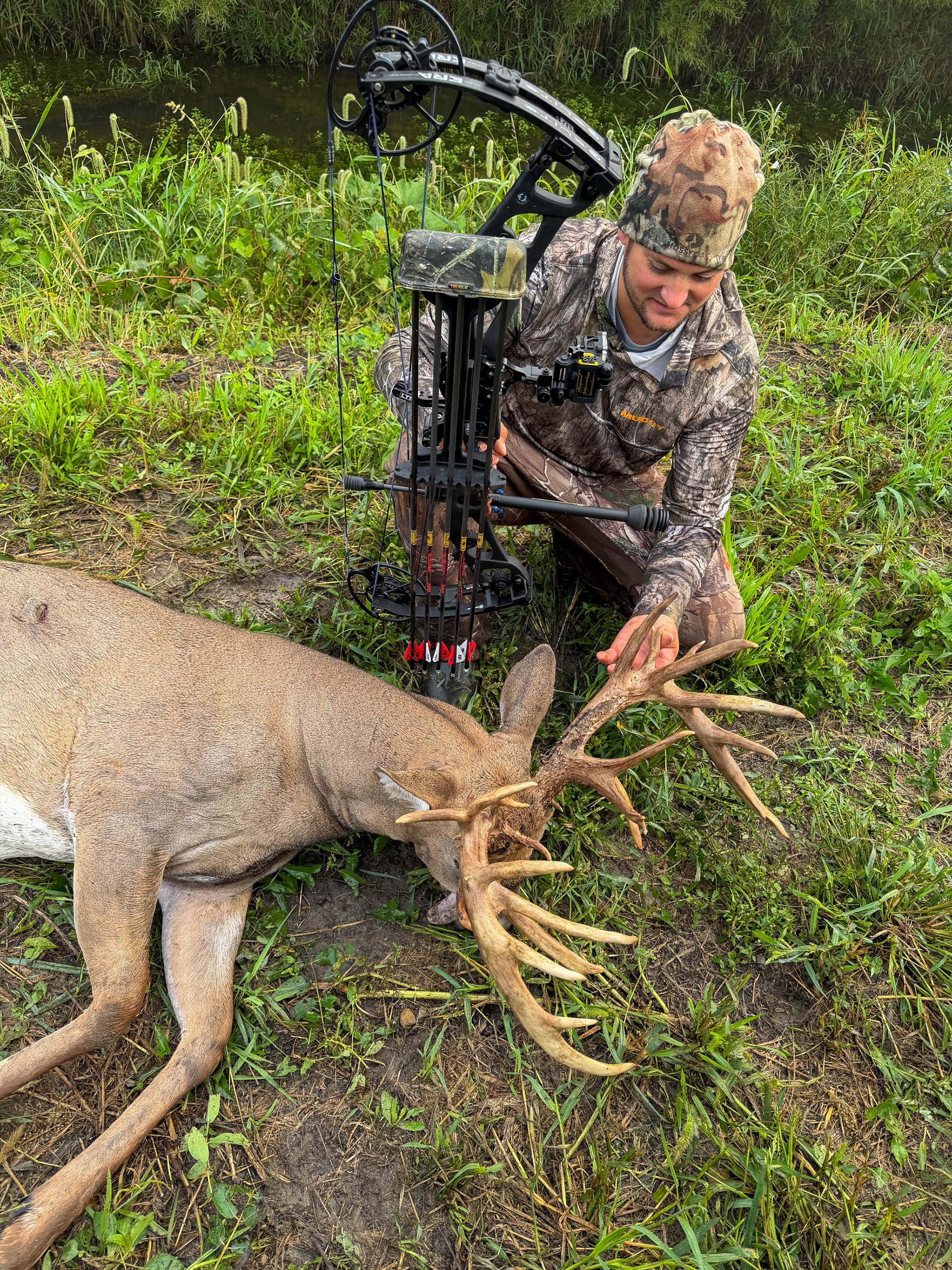 A photo of a bowhunter admiring a big Ohio buck.