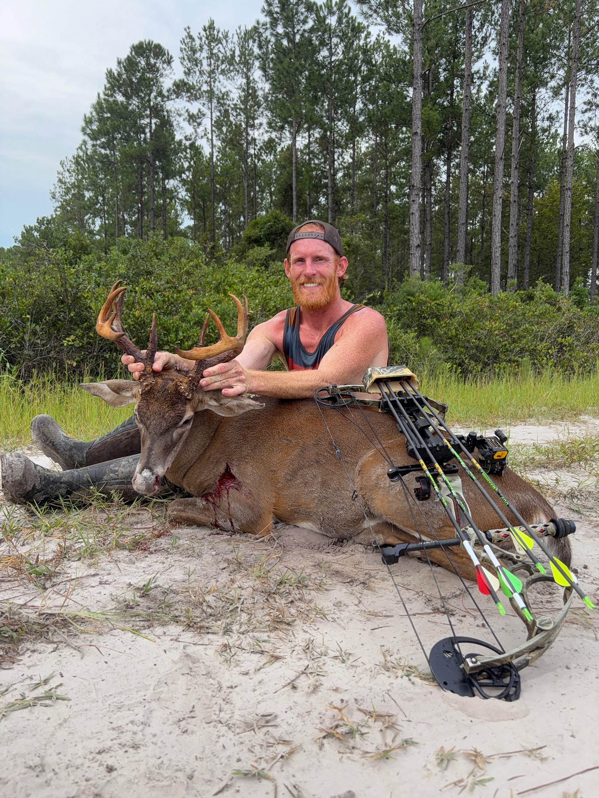 A Florida bowhunter sits behind a deer in the sand
