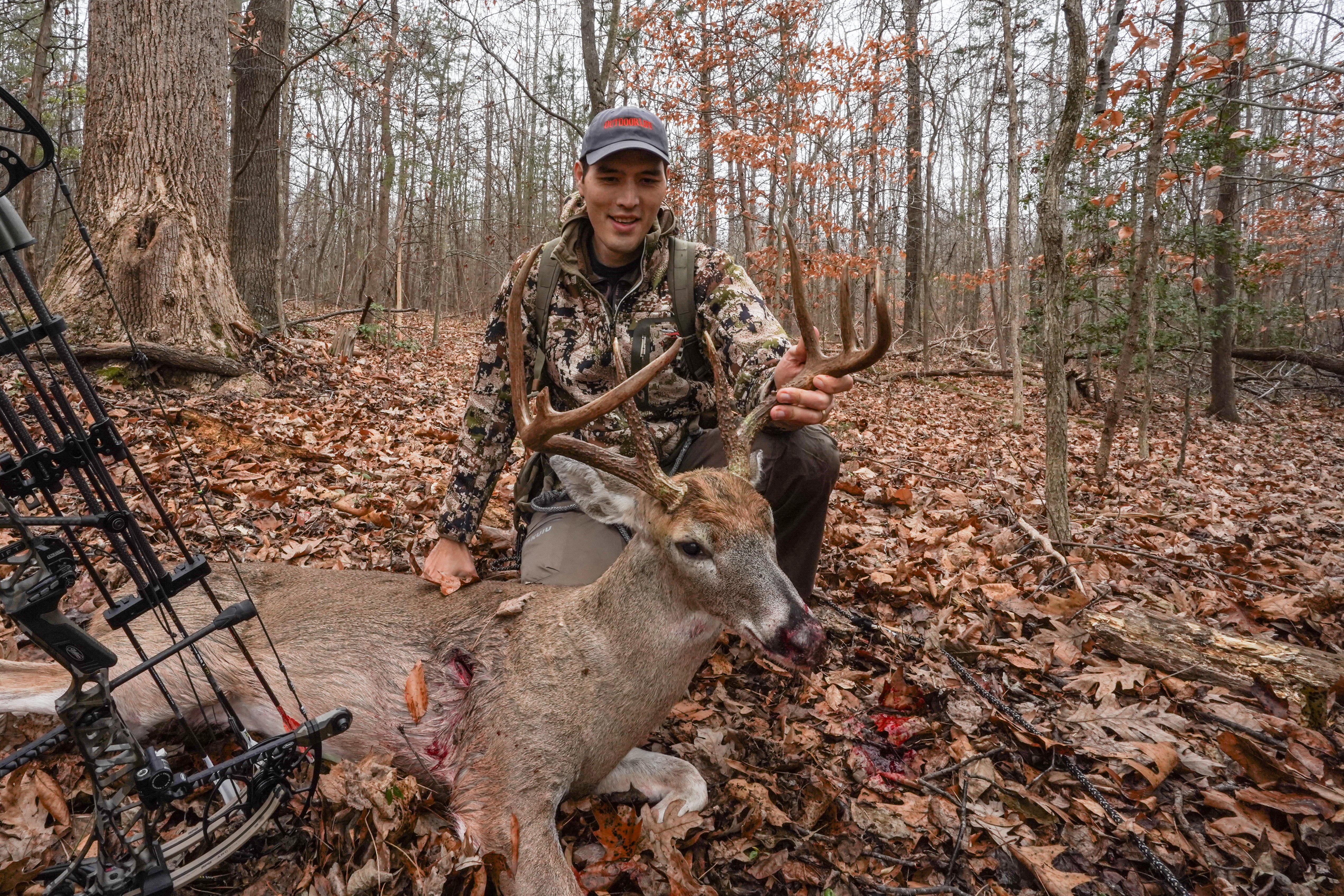 A hunter kneeling beside a buck