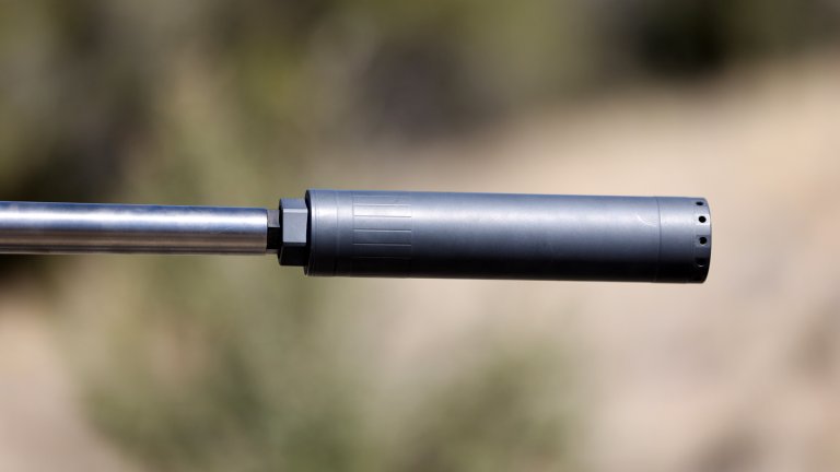 A suppressor in the foreground with a blurred natural background