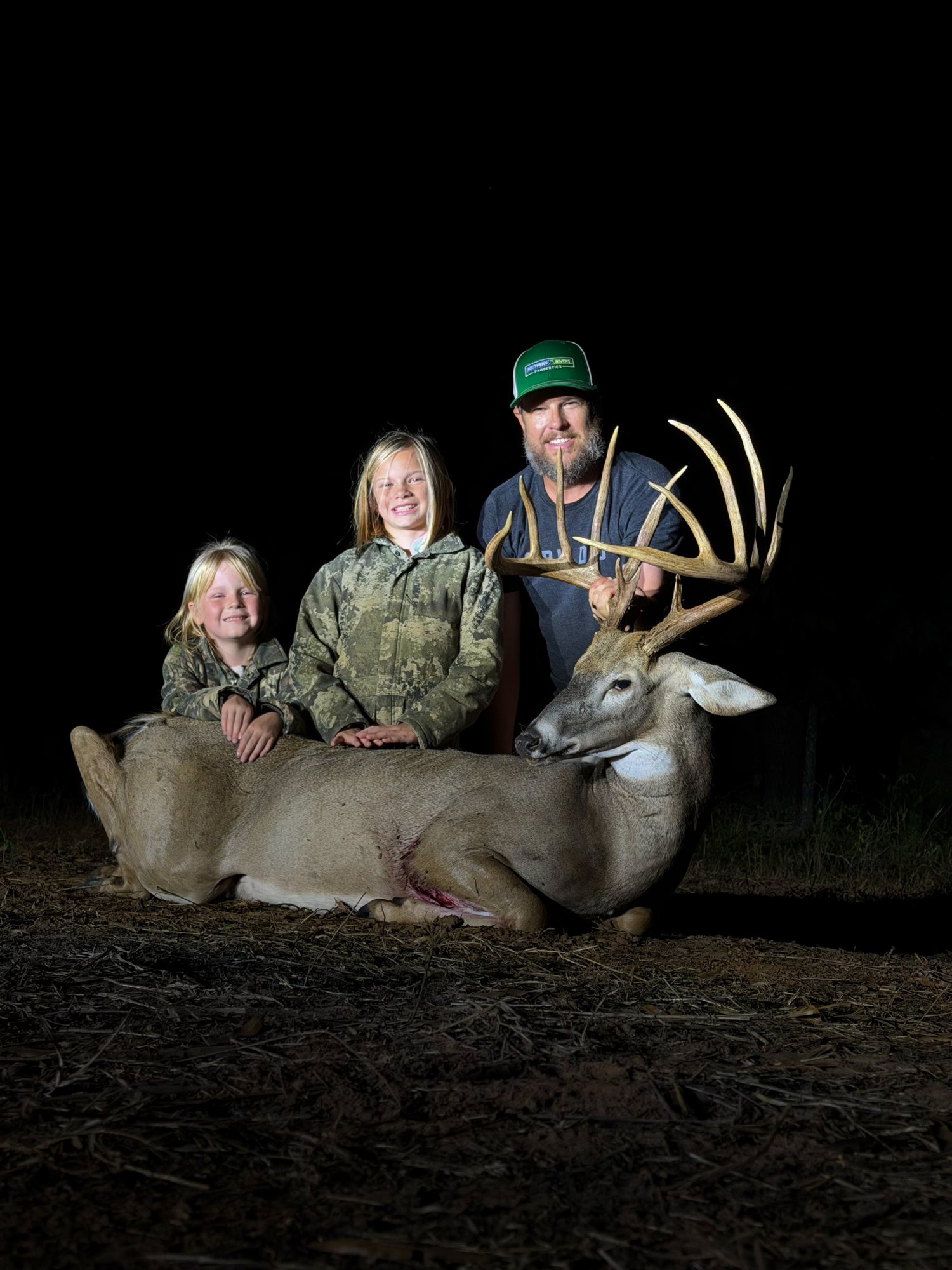 A dad with his two daughters with a nice buck.
