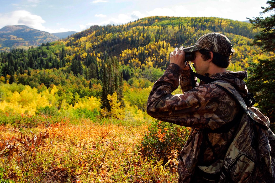 A hunter glasses with changing leaves in the background in colorado.