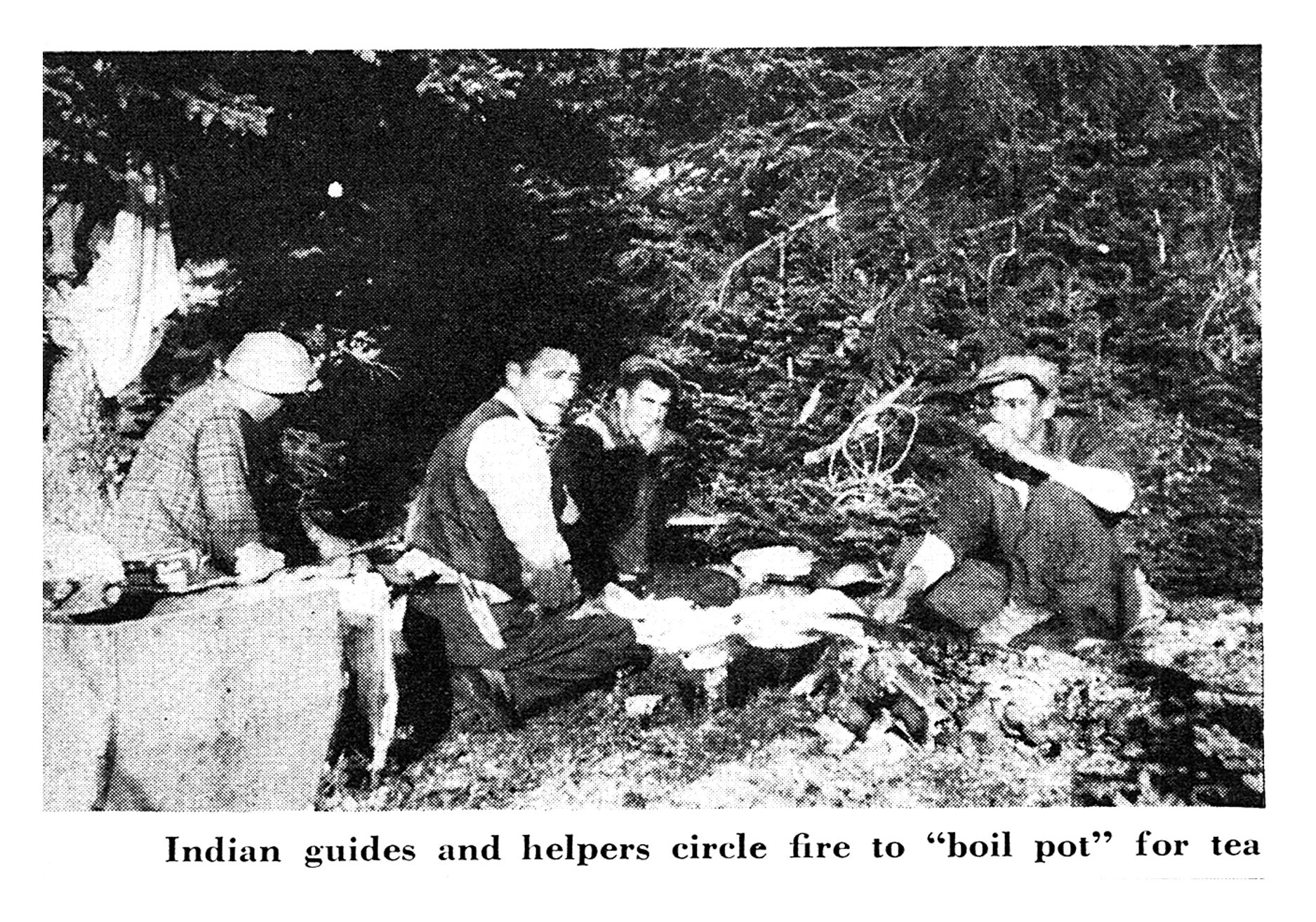Black-and-white photo of hunting guides and camp helpers sitting around a small fire in the woods, boiling water for tea.