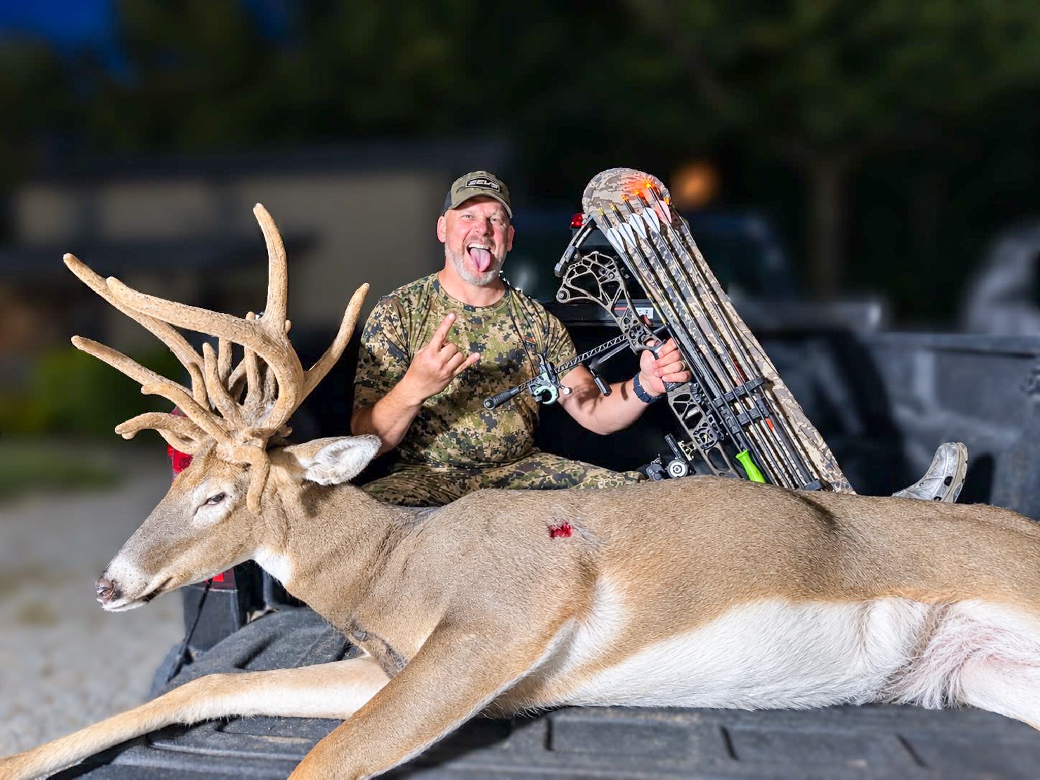 bowhunter with a velvet deer on tailgate rock on sign